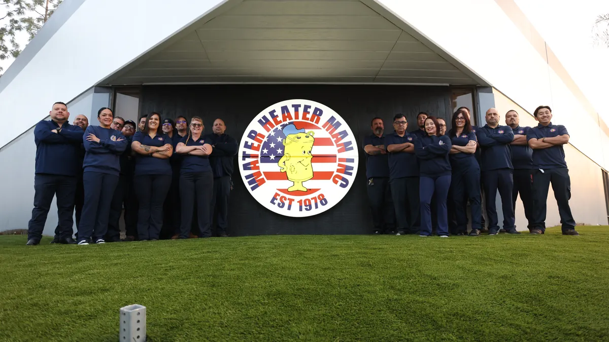 The Water Heater Man team in front of their logo at the shop